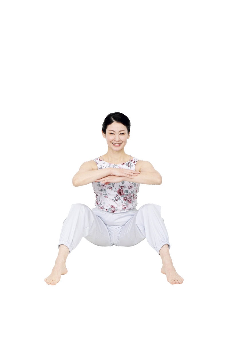 膝を開いて座り、手を組む
