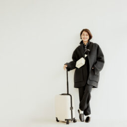 コート¥253,000／ポステレガント、ニット¥27,940、パンツ¥33,990／ともにエイチビューティ＆ユース（エイチ ビューティ＆ユース）、バッグ¥269,500／ヴァレクストラ（ヴァレクストラ・ジャパン）、ピアス¥46,200、リング各¥24,200／すべてヒロタカ（ヒロタカ 表参道ヒルズ）、ソックス¥3,520／マルコモンド（スティーブン アラン シンジュク）、靴¥128,700／セルジオ ロッシ（セルジオ ロッシ ジャパン カスタマーサービス）、スーツケース¥118,800／リモワ（リモワ クライアントサービス）、スカーフ／スタイリスト私物