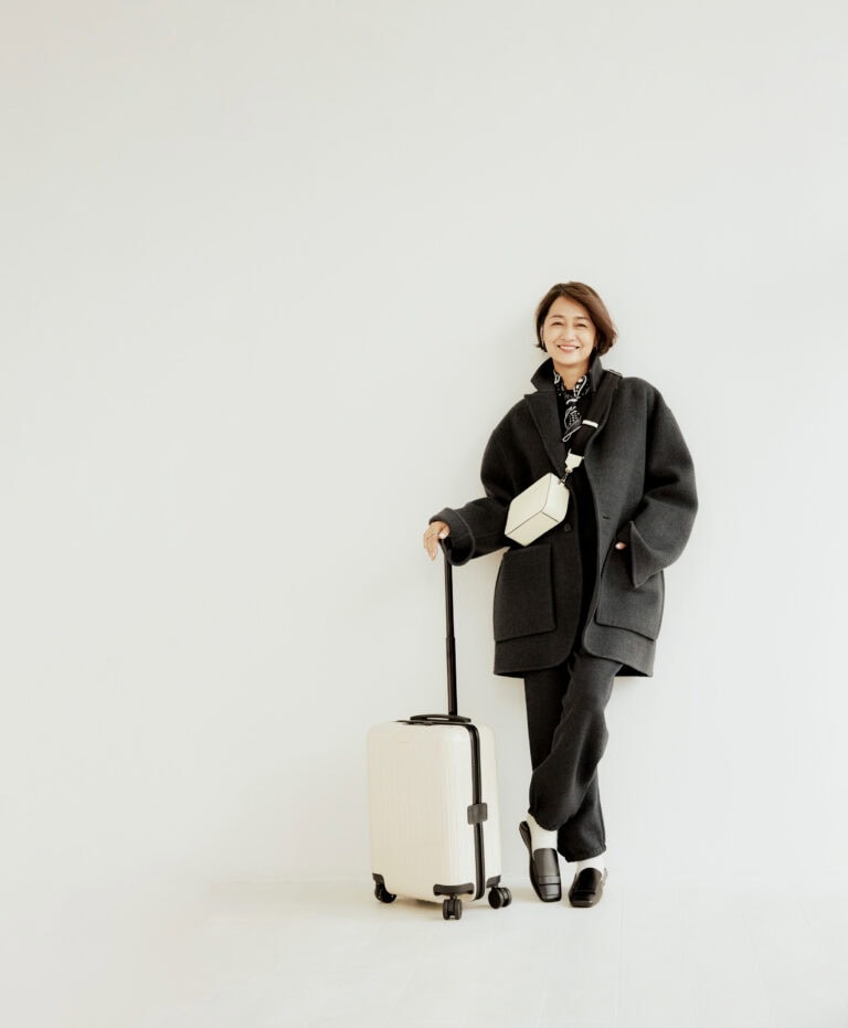 コート¥253,000/ポステレガント、ニット¥27,940、パンツ¥33,990/ともにエイチビューティ&ユース(エイチ ビューティ&ユース)、バッグ¥269,500/ヴァレクストラ(ヴァレクストラ・ジャパン)、ピアス¥46,200、リング各¥24,200/すべてヒロタカ(ヒロタカ 表参道ヒルズ)、ソックス¥3,520/マルコモンド(スティーブン アラン シンジュク)、靴¥128,700/セルジオ ロッシ(セルジオ ロッシ ジャパン カスタマーサービス)、スーツケース¥118,800/リモワ(リモワ クライアントサービス)、スカーフ/スタイリスト私物