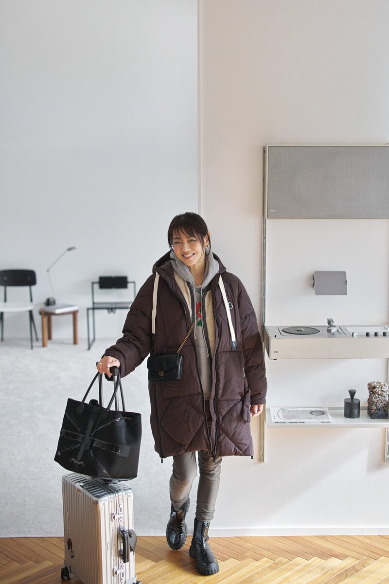 中綿コート、リバーシブルベスト／ともにオットダム、フーディ／グッチ、パンツ／カリアング、ピアス／ヴァンクリーフ＆アーペル、ポシェット／ローレン ラルフ ローレン、バッグ／A.D.M.J.、スーツケース／リモワ、ブーツ／ノーネーム（すべて私物）