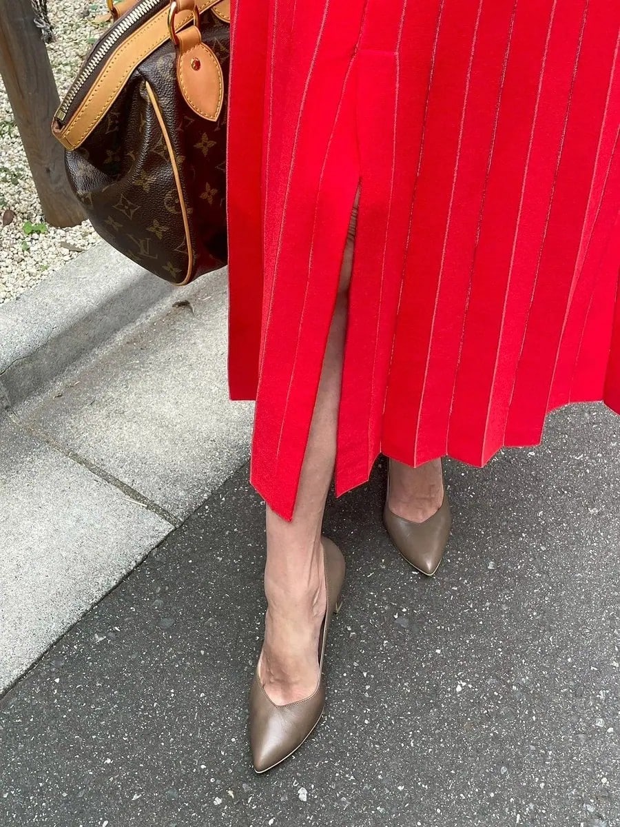 「靴は、『ダイアナ』淡い色味のカーキで、いろんな服に合わせられて出番が多い靴です。秋冬にぴったりのニュアンスカラーでオレンジのセットアップとも相性良いです。スカートのスリットが、脚がきれいに見える絶妙な開きは膝の少し上と思っていて、普段は自分で縫って調整しています」