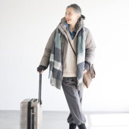 ダウンコート¥17,900，アームウォーマー¥1,500／ともにユニクロ、セーター¥19,990、デニムシャツ¥8,590／ともにザラ（ザラ カスタマーサービス）、パンツ¥47,300／エズミ（リ デザイン）、スニーカー¥35,200／ノーネーム（ストックマン）、バッグ¥20,900／リンク、ストール¥3,990、中にかけたサコッシュ¥1,290、キャリーケース¥19,900／すべて無印良品（無印良品 銀座）