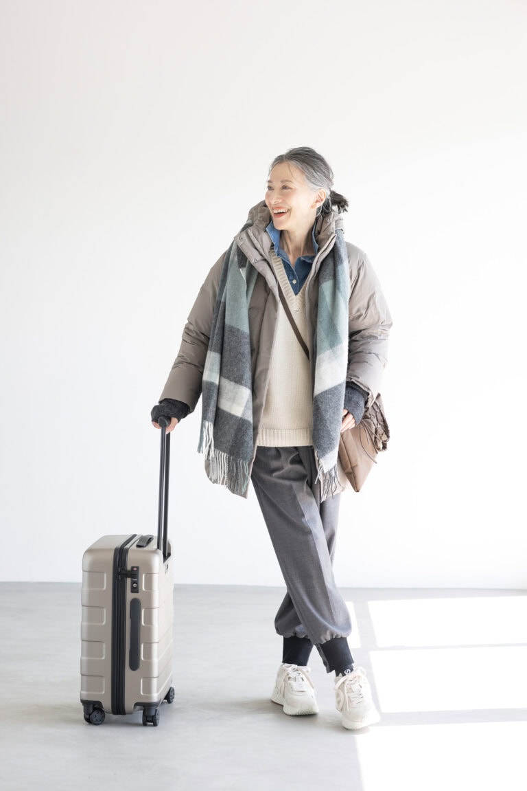 ダウンコート¥17,900,アームウォーマー¥1,500/ともにユニクロ、セーター¥19,990、デニムシャツ¥8,590/ともにザラ(ザラ カスタマーサービス)、パンツ¥47,300/エズミ(リ デザイン)、スニーカー¥35,200/ノーネーム(ストックマン)、バッグ¥20,900/リンク、ストール¥3,990、中にかけたサコッシュ¥1,290、キャリーケース¥19,900/すべて無印良品(無印良品 銀座)