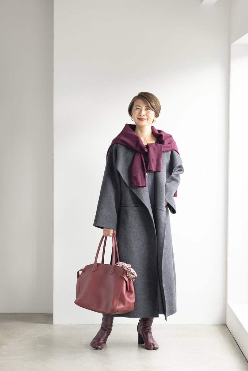 コート／トーテム、ワンピース／マイカ＆ディール、肩がけしたニット／ネミカ、ピアス／ザラ、ネックレス、ブレスレット、リング／すべてイシス、バッグ／ヒロフ、手に持ったストール／エルメス、ブーツ／メゾン マルジェラ（すべて私物）