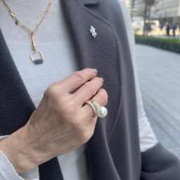 「コーデ全体はクールな雰囲気にしたので、華やかなアクセサリーでエレガントな雰囲気に。大人遊びを効かせたヤモリのピンブローチは小さなパールがついていて、大ぶりなパールのリングとリンク。ゴールドのネックレスは、トップにグレーのレザーがあしらわれているので、ジレ＆コートやバッグとリンクさせ、コーディネートに統一感を持たせています」