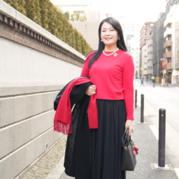 コートを脱いでみると鮮やかな赤ニットが際立ち、顔まわりが明るく映えます。