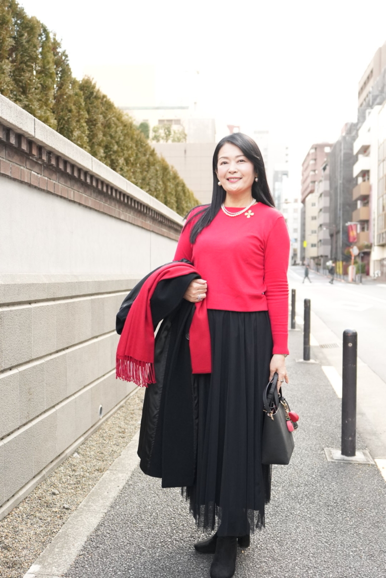 コートを脱いでみると鮮やかな赤ニットが際立ち、顔まわりが明るく映えます。