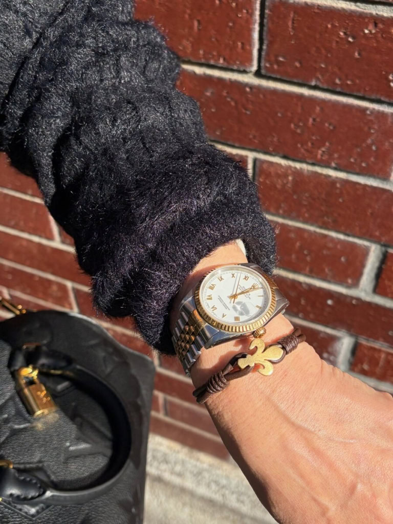 ブラックのワントーンコーデに、「ロレックス」の時計と、フィレンツェのシンボルマークがあしらわれた「ウミリス」のブレスレットを重ねづけし、さりげないレイヤードが上品な手元を演出。「インパクトのある『ロレックス』に、暖かみのあるゴールドアクセサリーを合わせて、女性らしい印象にしました」