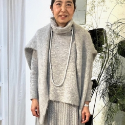 「グレーのワントーンスタイルでまとめました」と三好さん。「ワントーンコーデは、すっきり見せしてくれるので、バランスがまとまりやすいのですが、単調になってしまう場合もあるので、柄物スカートやニットカーディガンなどをアクセントに」。肩掛けしたニットとスカートは、ル シェル ド ハリス。同系色のオフタートルニットはベラ ジョーンズのもの。ハリスのパールロングネックレスをオン。