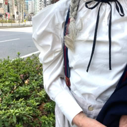 「インナーのブラウスは肩まわりのフォルムが構築的。１枚で着ても着映えるアイテムで重宝しています。首元には黒のボウタイでフェミニンながらも知的なアクセントとしてプラスしています」