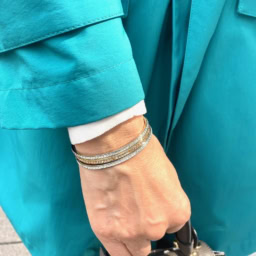 「ハンドメイドのバングルは、シルバーとゴールドのバングルをレイヤード。スプリングコートのボタンとリンクさせ、エレガントなポイントとして効かせています」