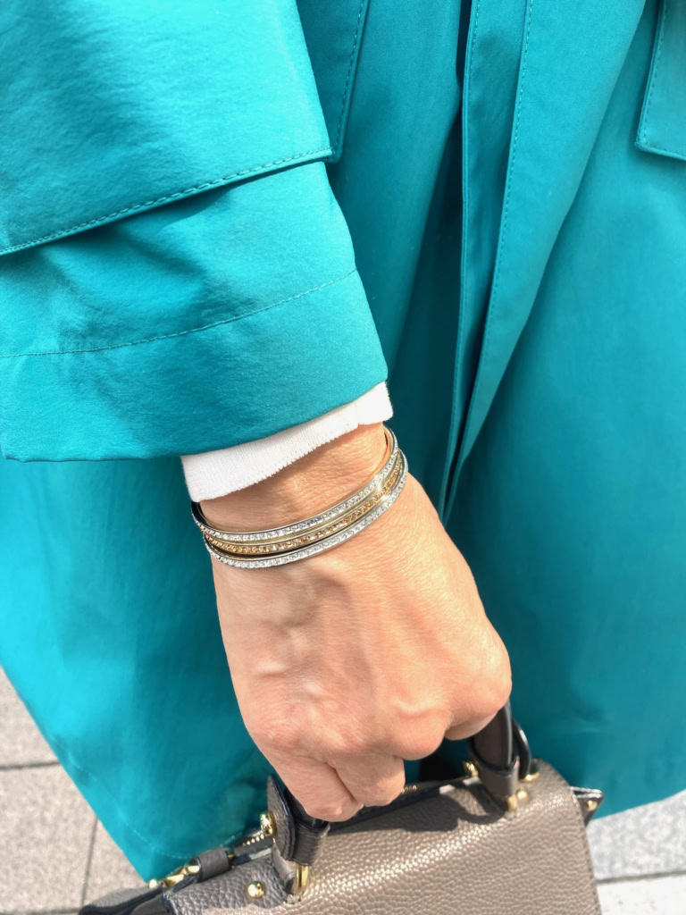 「ハンドメイドのバングルは、シルバーとゴールドのバングルをレイヤード。スプリングコートのボタンとリンクさせ、エレガントなポイントとして効かせています」