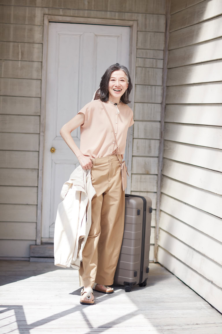 ブラウス¥3,990、手に持ったジャケット¥5,990、ミニサコッシュ¥1,290、スーツケース¥31,900/すべて無印良品(無印良品 銀座)、パンツ¥3,990/ユニクロ、ハット¥6,990/プラステ、シューズ¥28,600/ビルケンシュトック(ビルケンシュトック・ジャパン カスタマーサービス)