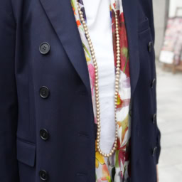 「スーツはともするとビジネスライクにも見えてしまうので、カラフルな花柄のスカーフとパールのロングネックレスをプラス。やわらかくエレガントな印象に仕上がります」