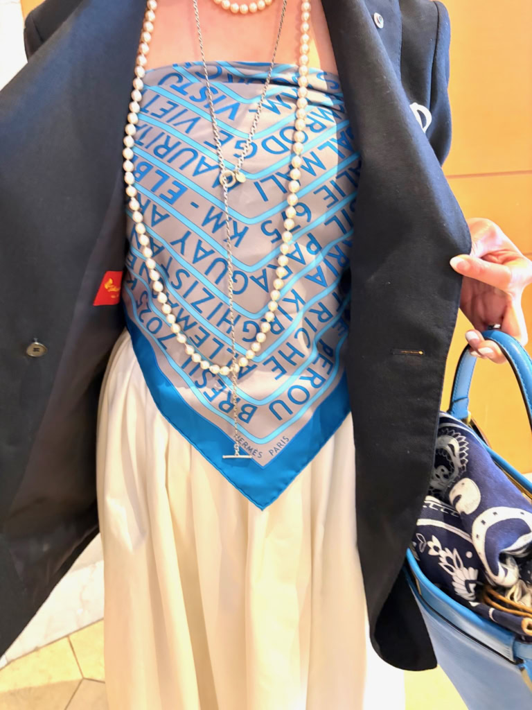 「エルメス」のスカーフをビスチェ風に巻いて、インナーに使うという大胆なアイデアが、「ドゥーズイエムクラス」の定番紺ブレを一気に個性的で華やかな印象に。 「スカーフの鮮やかなブルーカラーが、紺ブレの色に合っていると感じて、クルッと巻いてみました。クリップ同様、ちょっと遊び心で楽しんでいます」