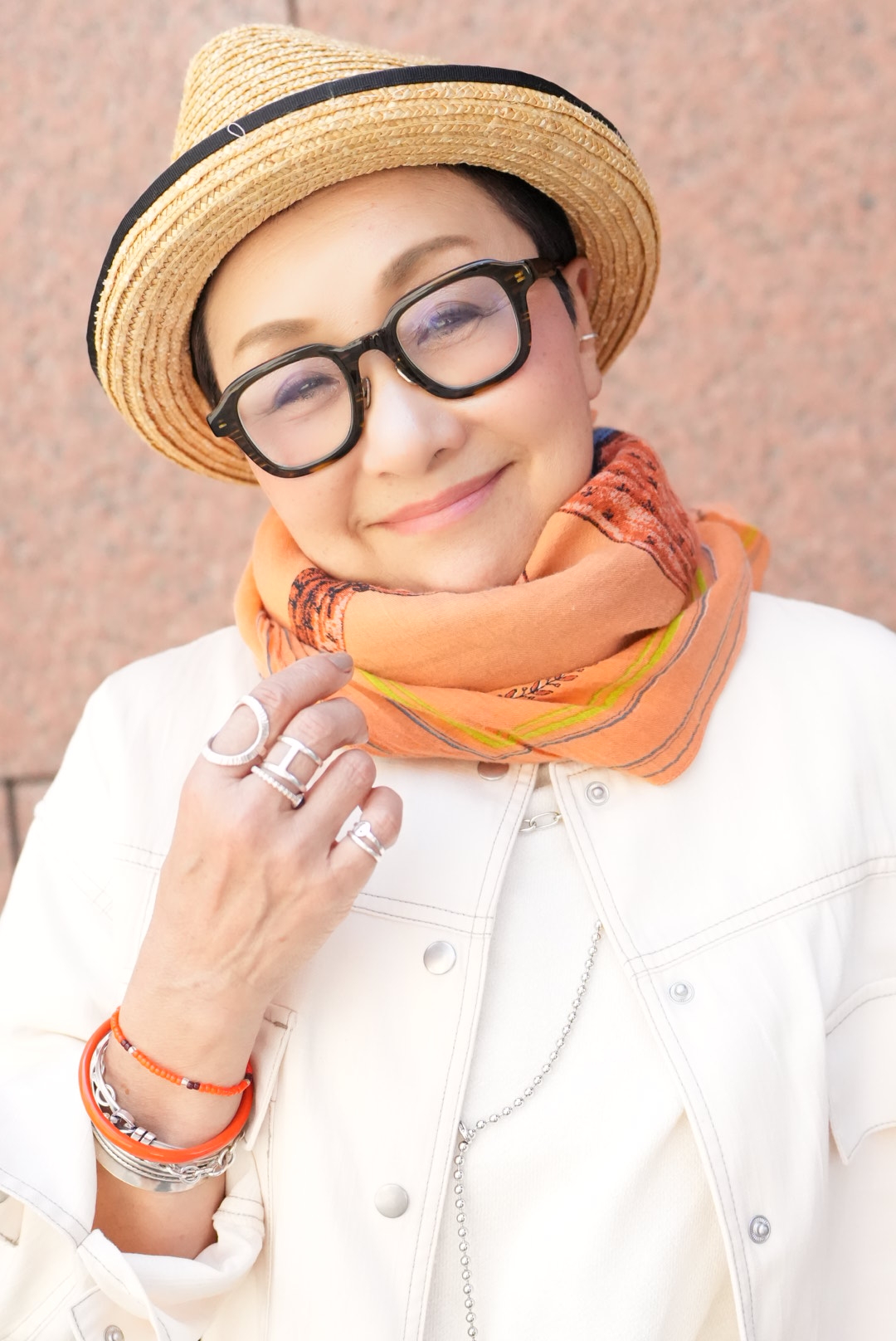 「アクセサリーやストールなどの小物をシルバー×オレンジに。フレッシュで夏っぽい印象に仕上がりました。コーデ全体がホワイトベースなので、黒縁メガネが際立ち顔まわりが引き締まって見えます」