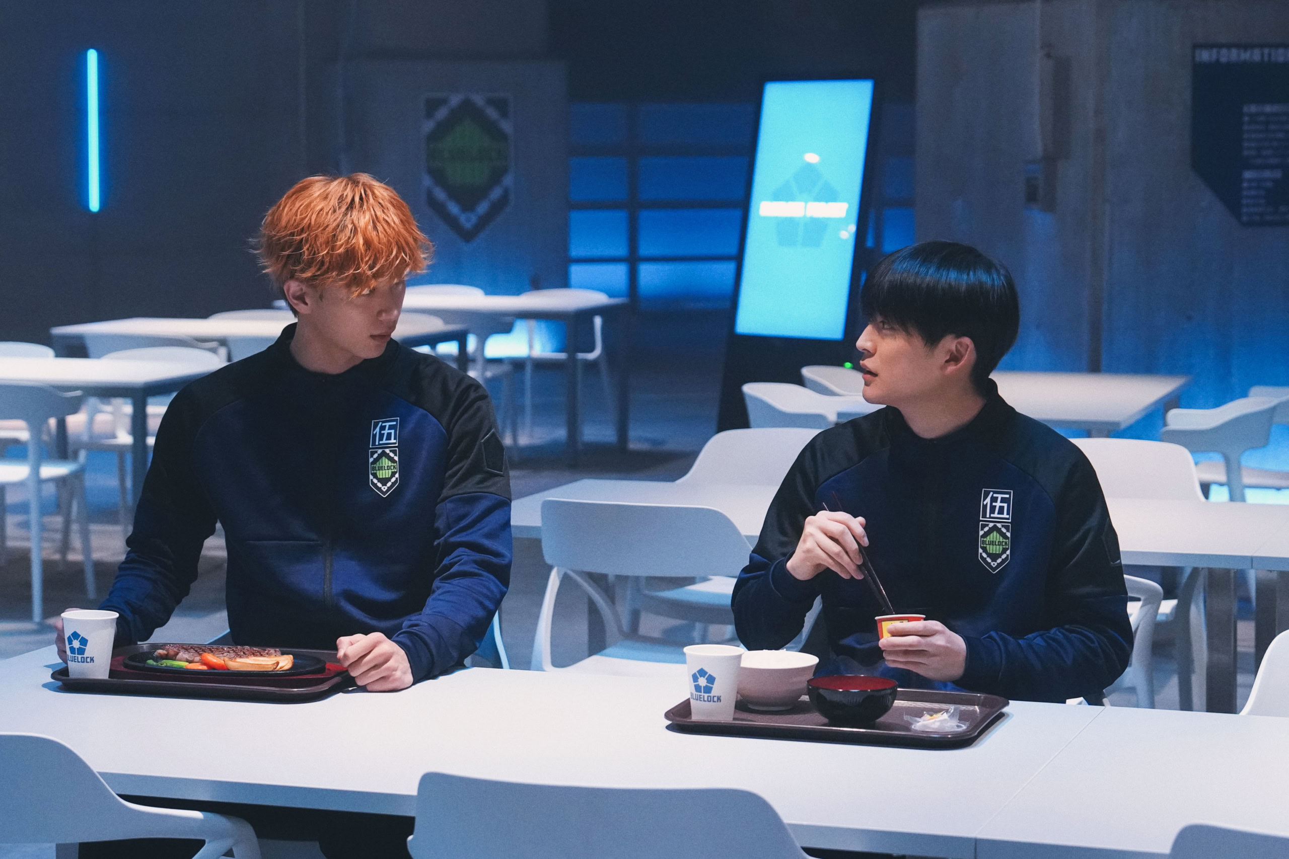 映画『ブルーロック』より食堂で会話する國神錬介(野村康太)と潔世一(高橋文哉)